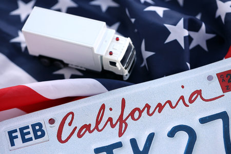 Toy truck and USA state of California license plate on US flag. Concept of driving in California. Reaching a driving permitの写真素材