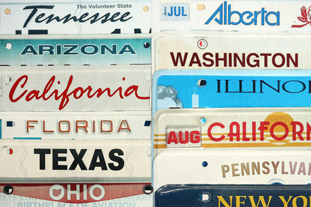 Old US car license plates with various state names. Concept of driving in United States. Reaching a car registrationの写真素材