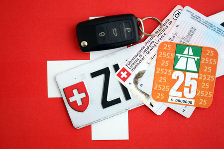Switzerland vignette sticker for 2025 year and license plate with ignition key on Swiss flag close up. Driving permit and registration conceptの写真素材