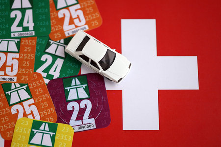 Switzerland vignette stickers for different years with toy car on Swiss flag close up. Driving permit and registration conceptの写真素材
