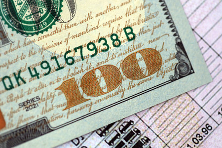 Hundred dollar bill on US driver license close up. Concept of driving lessons or automobile taxpayingの写真素材