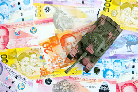 Philippines peso currency money bills and toy tank close up. The concept of army funds and weapons salesの写真素材