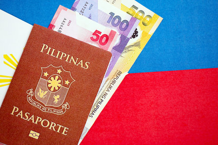 Philippines peso currency money bills and passport lies on flag close up. The concept of travel and vacationの写真素材