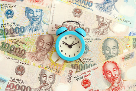 Vietnamese dong currency money bills and alarm clock close up. The concept of time management and incomeの写真素材