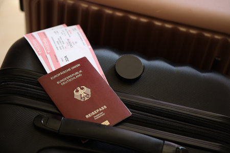 Germany passport with tickets lies on touristic suitcase close up in airport waiting hall. Travel worldwide and international tourism conceptの写真素材