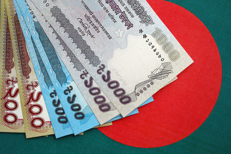 Bangladeshi taka money bills in big amount lies on Bangladesh flag close up. Finance and banking...