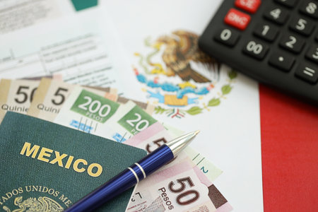 Mexican pesos money bills in big amount lies on table with pen, calculator, passport and tax forms close up. Finance and banking conceptの写真素材