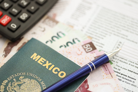 Mexican pesos money bills in big amount lies on table with pen, calculator, passport and tax forms close up. Finance and banking conceptの写真素材