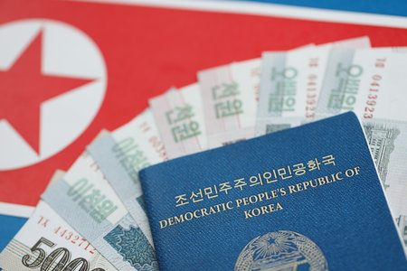 North Korean won money bills in big amount and passport lies on flag close up. Finance and banking conceptの写真素材