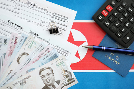 North Korean won money bills in big amount lies on table with pen, calculator, passport and tax forms close up. Taxpaying and accounting conceptの写真素材