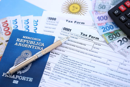 Argentine pesos money bills in big amount lies on table with pen, calculator, passport and tax forms close up. Finance and banking conceptの写真素材