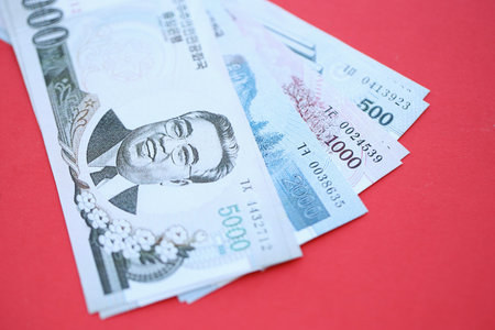 North Korean won money bills in big amount lies on red color table close up. Finance and banking conceptの写真素材
