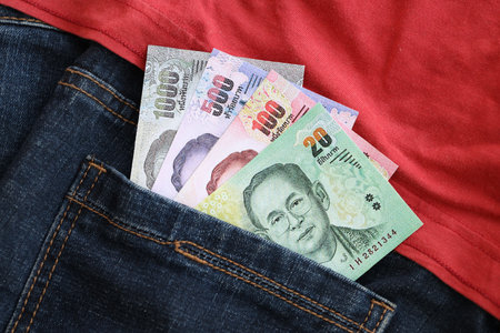 Thai baht money bills in denims pocket close up. The concept of fashion and wealthの写真素材