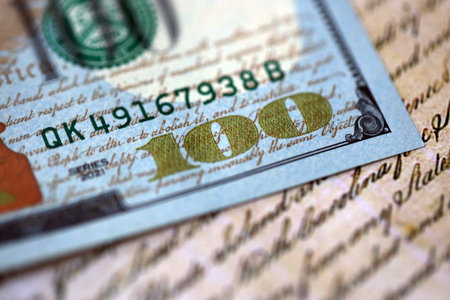 One hundred US dollar bills and United States Constitution page fragment. Concept of lawsuit in...