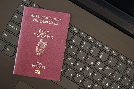 Ireland passport lies on black laptop keyboard buttons background close up. Technologies and control in Europe conceptの写真素材