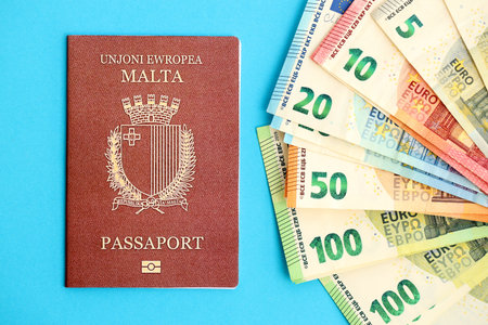 Malta passport lies with euro money banknotes on blue background close up. Salary and pension in Europe conceptの写真素材