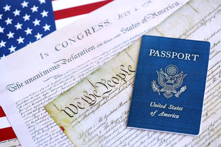 US passport on replica pages of the United States Constitution close up with US flag background
