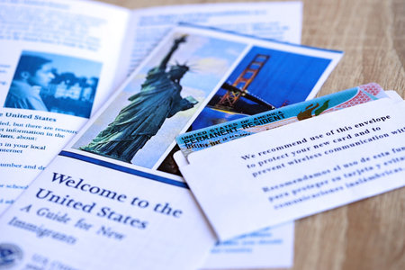 Permanent resident green card in envelope and guide for new immigrants lies on wooden table close upの写真素材