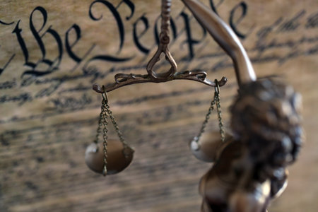 Dark scene with Lady Justice and background of US Constitution page. Lawsuit and judgement in United...