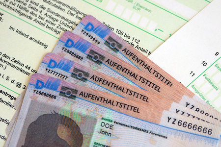 German Permanent resident specimen cards lies on german tax form close up. Aufenthaltstitel and einkommensteuererklarungの写真素材