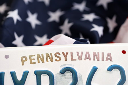 USA state of Pennsylvania license plate on US flag. Concept of driving in Pennsylvania. Reaching a driving permitの写真素材