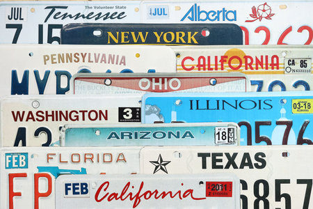 Old US car license plates with various state names. Concept of driving in United States. Reaching a car registration