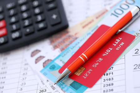Credit card and pen with russian ruble currency money bills banknotes on calculations document background. Business, financial operations and accounting in Russian Federationの写真素材