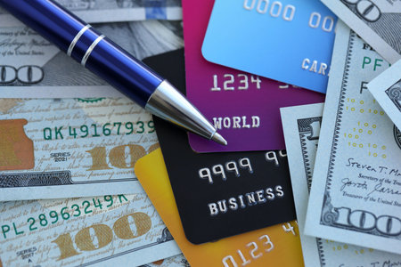 One hundred US dollar bills and silver pen with credit cards close up. Concept of business calculating and accounting in United Statesの写真素材