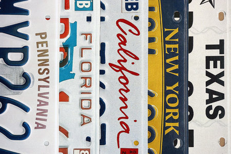 Old US car license plates with various state names close up. Concept of driving in United States. Reaching a car registrationの写真素材