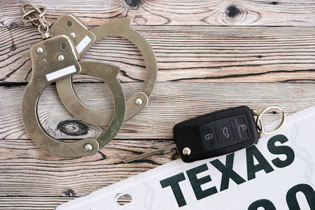 Remote control car keys on Texas license plate and handcuffs.