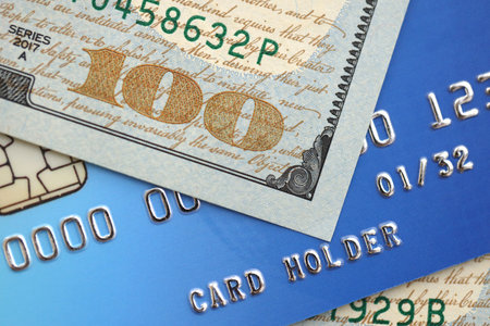 One hundred US dollar bill banknote on blue credit card for banking and payments. Concept of business and bank serviceの写真素材