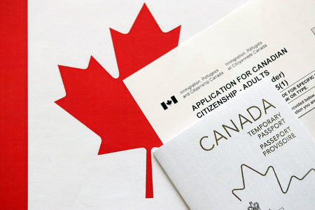 Canadian temporary passport and application for canadian citizenship lies on flag close upの写真素材
