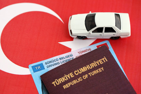 Turkiye driving permit concept. Driver license with passport and toy car on turkish flag close upの写真素材