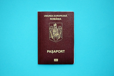 Romanian passport book on light blue paper background close up. Travel document on blue surfaceの写真素材