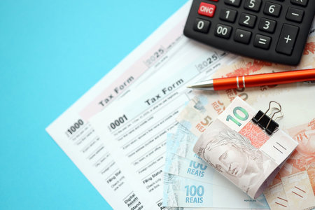 Brazilian reais banknotes with calculator and tax form. The current Brazil real money bills and tax...