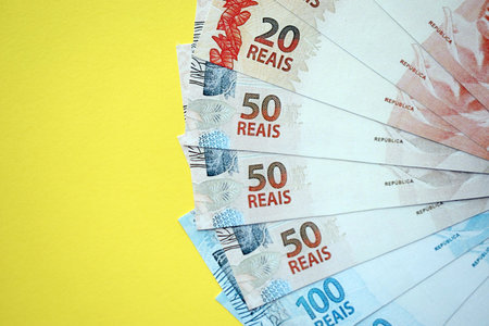 Close up of brazilian reais money bills in big amount on yellow table. Pile of Brazil real currency banknotes. Finance and banking conceptの写真素材