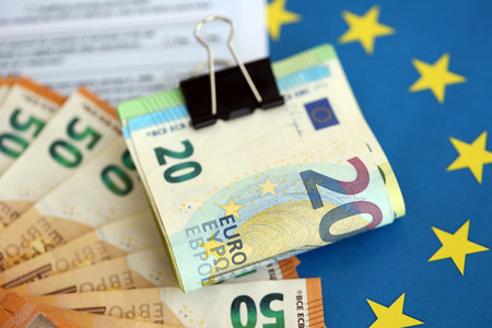 European euro currency money notes bunch on tax form and European union blue flag close up. Concept of taxation and accounting in Europeの写真素材