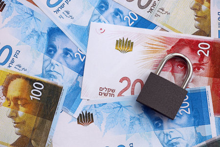 Israel New Shekels banknotes and padlock. The current Israel money bills and lock lies on table in big amount. The concept of sanctions and financial safety in Israelの写真素材