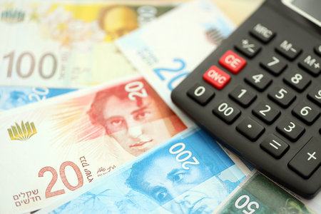 Israel New Shekels banknotes and calculator. The current Israel money bills and calc lies on table in big amount. The concept of taxation and money count in Israelの写真素材