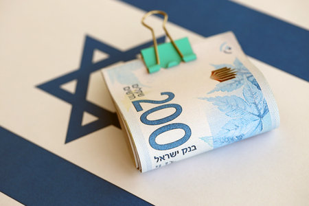 Israel New Shekels banknotes on national flag. The current Israel money bills lies on flag in big amount. The concept of business and investment in Israelの写真素材