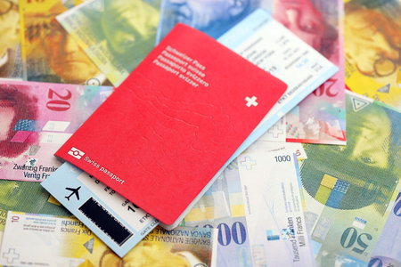 Swiss franc banknotes and passport with tickets. The current francs money bills and biometrical pass lies on table in big amount. The concept of travel and vacation in Switzerlandの写真素材