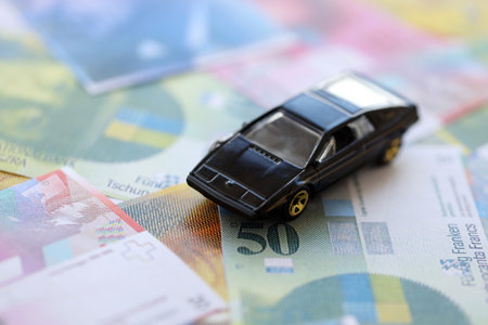 Swiss franc banknotes and toy car. The current francs money bills and black car lies on table in big amount. The concept of car ownership in Switzerlandの写真素材