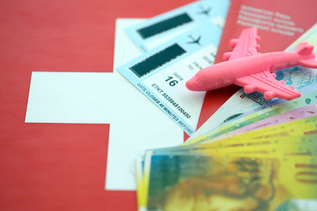 Swiss franc banknotes and passport with tickets on flag. The current francs money bills and biometrical pass lies on flag. The concept of travel and vacation in Switzerlandの写真素材