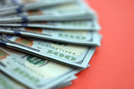 Big amount of United States hundred dollar bills on red background. Concept of taxation and money...