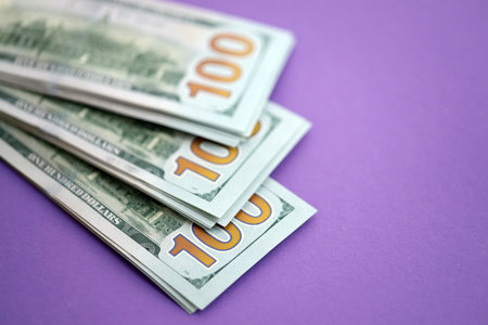 Big amount of United States hundred dollar bills on purple background. Concept of taxation and money making in United Statesの写真素材