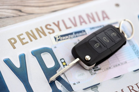 Remote control car keys on Pennsylvania license plate with driver license. Concept of driving in Pennsylvania. Reaching a driving permitの写真素材