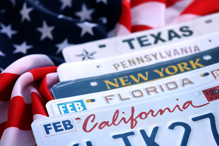 Old US car license plates with various state names on USA flag. Concept of driving in United States. Reaching a car registrationの写真素材