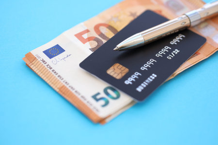 Credit card and pen with euro currency money bills on light blue background. Business, financial operations and accounting in European Unionの写真素材