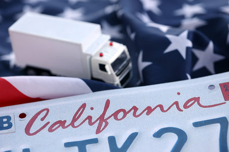 Toy truck and USA state of California license plate on US flag. Concept of driving in California. Reaching a driving permitの写真素材