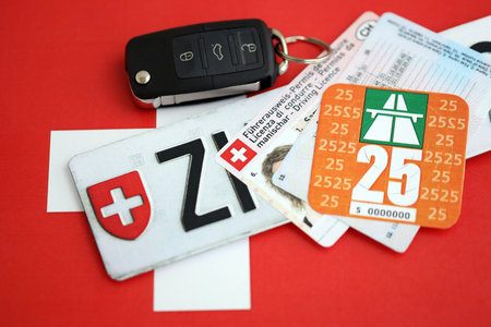 Switzerland vignette sticker for 2025 year and license plate with ignition key on Swiss flag close up. Driving permit and registration conceptの写真素材